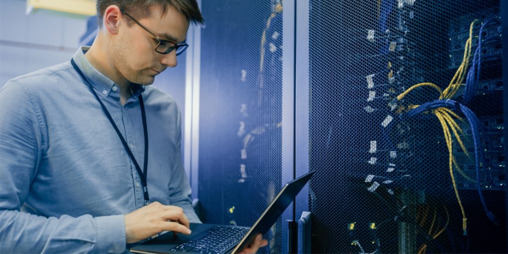 IT Professional working on a laptop next to a server